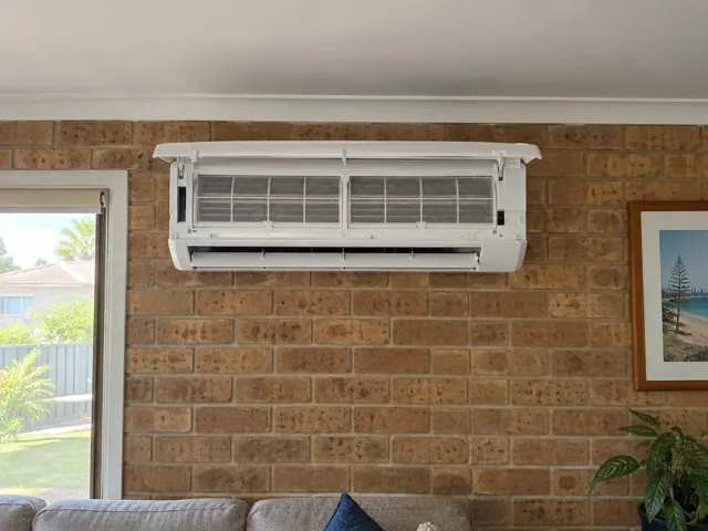 Clean split system indoor head on a brick wall with open front panel and visible filters in Runaway Bay